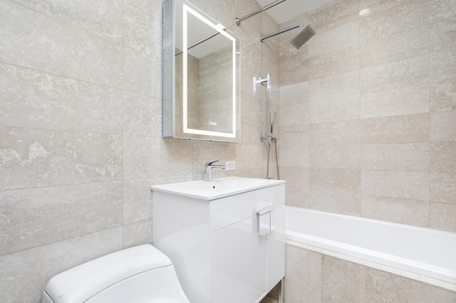 full bathroom featuring tile walls, vanity, toilet, and tiled shower / bath combo