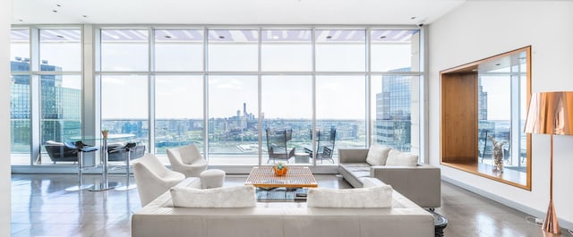 living area featuring a wealth of natural light, a view of city, baseboards, and expansive windows