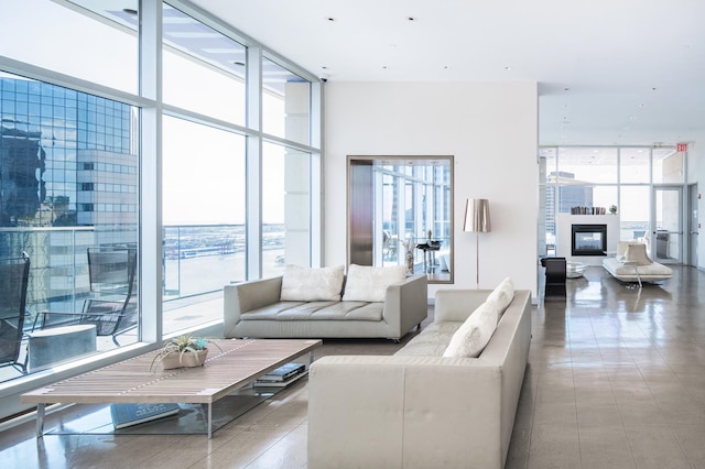 living area featuring a wall of windows, plenty of natural light, and a glass covered fireplace