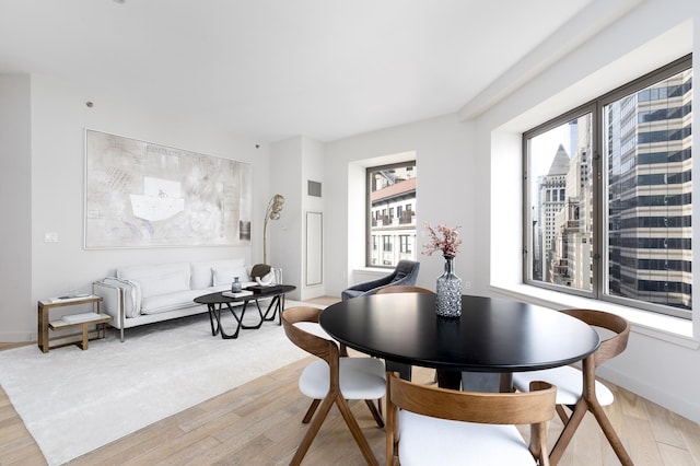 dining space featuring light wood finished floors and baseboards