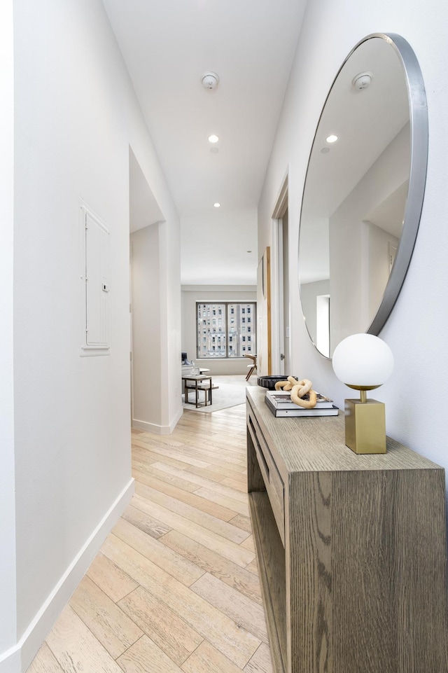 hall with recessed lighting, baseboards, electric panel, and light wood-style flooring