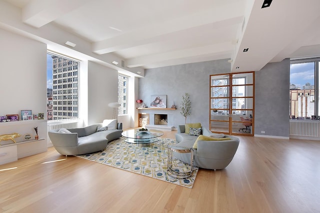 living room with a fireplace with raised hearth, baseboards, a view of city, light wood finished floors, and beamed ceiling