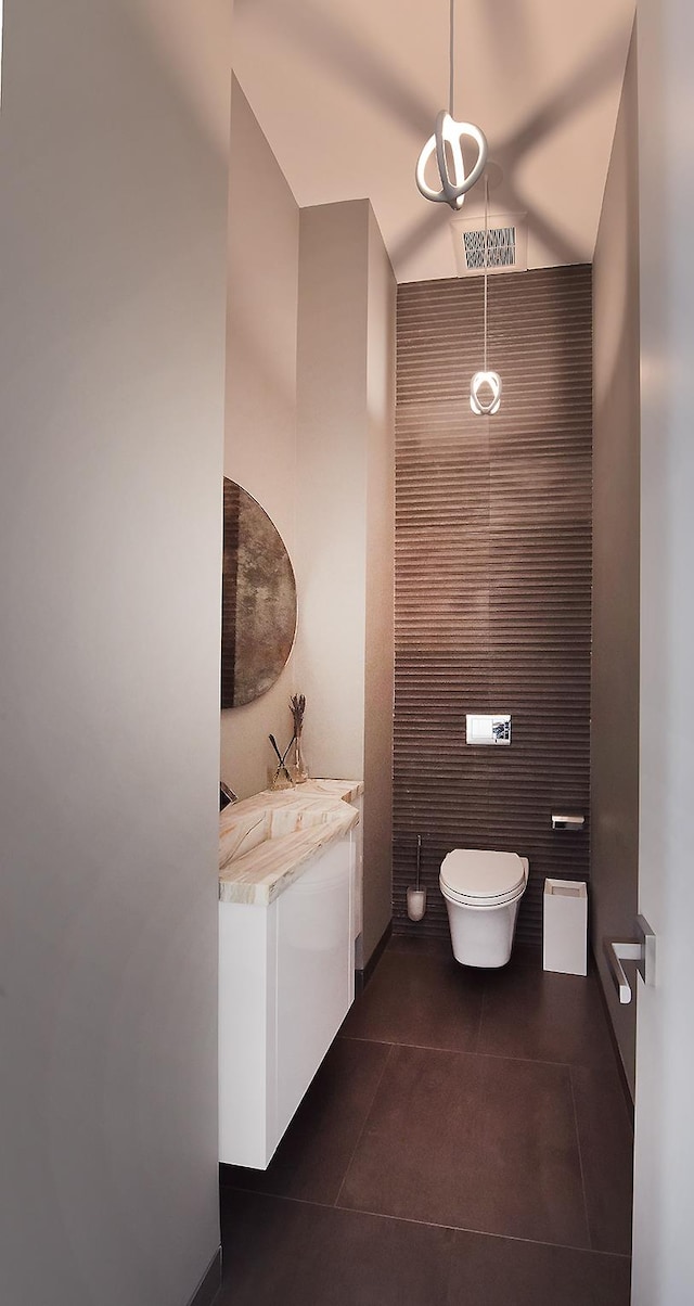 bathroom with tile patterned flooring, visible vents, toilet, vaulted ceiling, and vanity