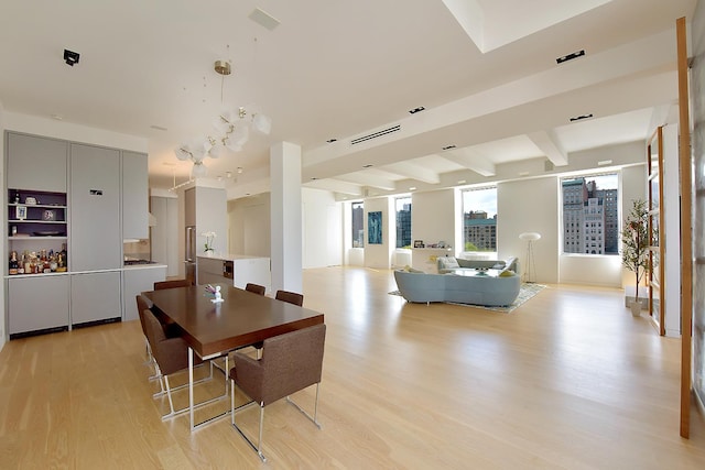 dining space featuring light wood-type flooring and beamed ceiling