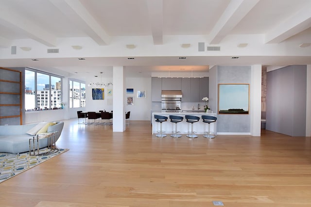 interior space featuring beam ceiling, light wood-style flooring, and visible vents