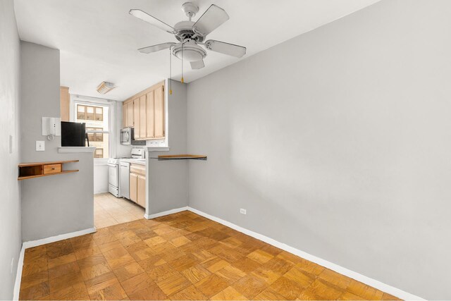 kitchen with white gas range oven, baseboards, ceiling fan, stainless steel microwave, and freestanding refrigerator