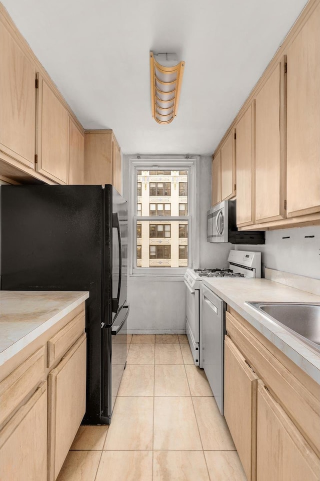 kitchen featuring light tile patterned floors, stainless steel appliances, light countertops, and light brown cabinetry