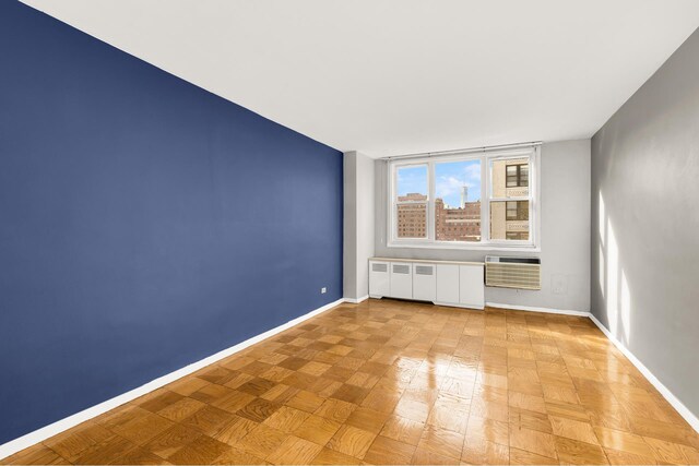 empty room with an AC wall unit and baseboards