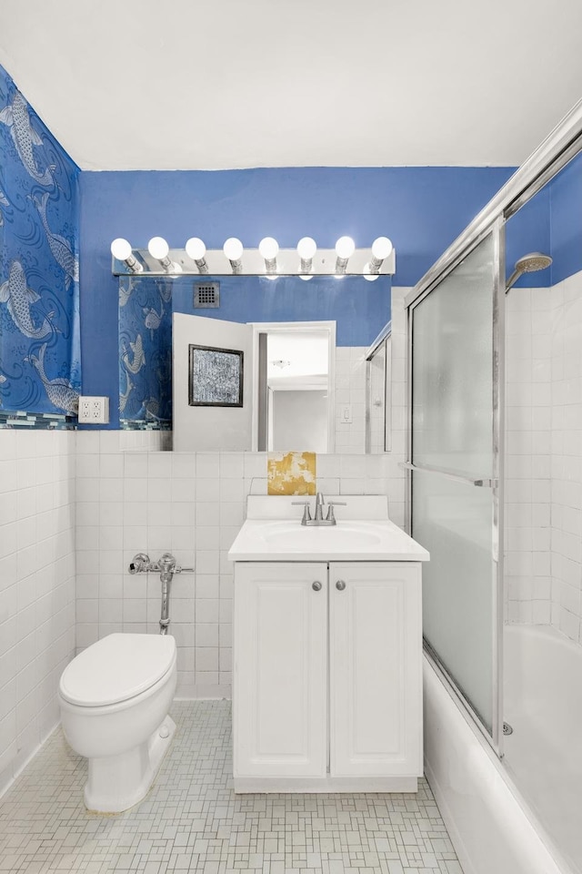 bathroom featuring toilet, vanity, tile walls, and tile patterned floors