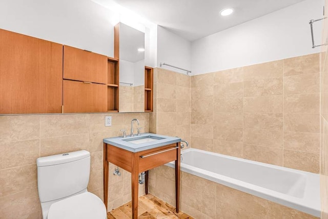 full bathroom featuring tile walls, sink, tiled shower / bath, and toilet