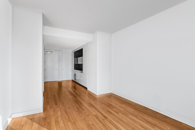 spare room featuring light wood-type flooring and baseboards