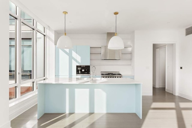 kitchen with hanging light fixtures, wood-type flooring, sink, and a center island with sink