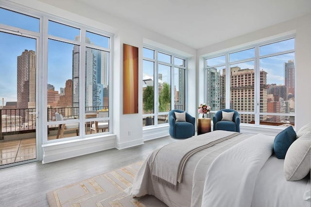 bedroom with multiple windows, hardwood / wood-style floors, and access to outside