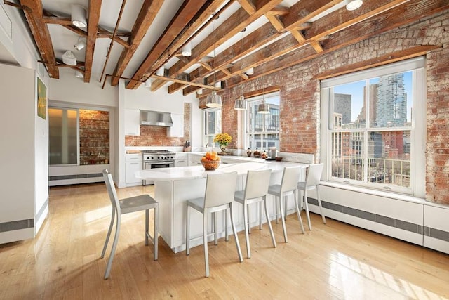 28 Laight St Unit 6Ab, New York City, NY 10013 - kitchen featuring white cabinetry, wall chimney range hood, high end range, and brick wall