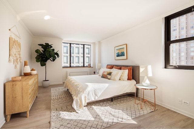 bedroom featuring light wood-type flooring, baseboards, and crown molding