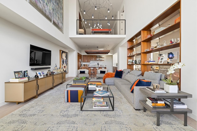 living room with a notable chandelier, a high ceiling, and wood finished floors