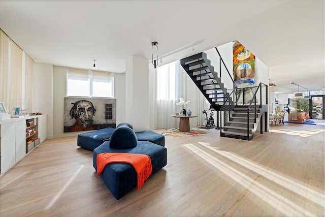 sitting room with a wealth of natural light, light wood-type flooring, stairway, and track lighting