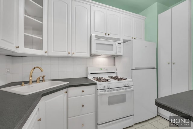 kitchen featuring white appliances, white cabinets, backsplash, and a sink