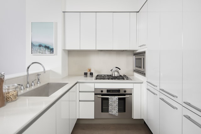 kitchen with stainless steel appliances, light countertops, white cabinetry, and a sink