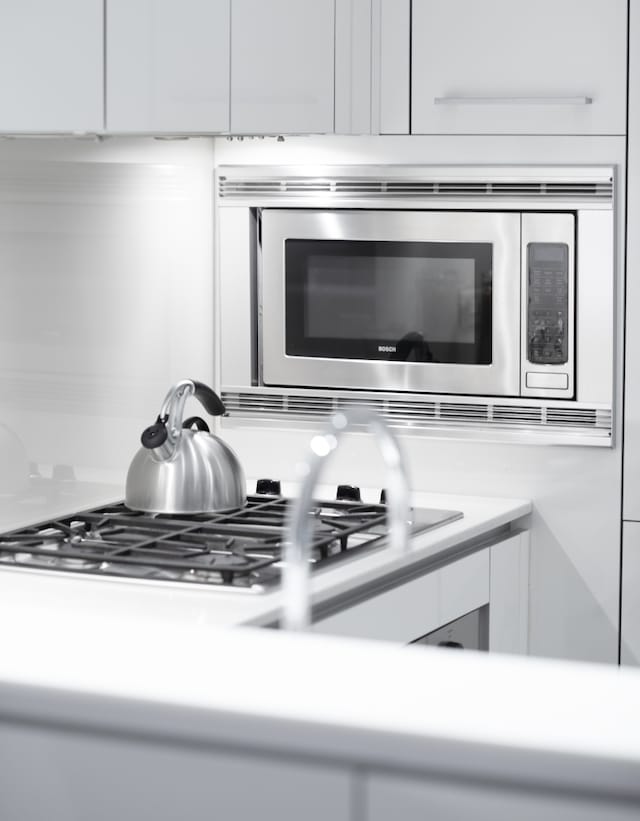 interior details featuring appliances with stainless steel finishes, white cabinets, and light countertops