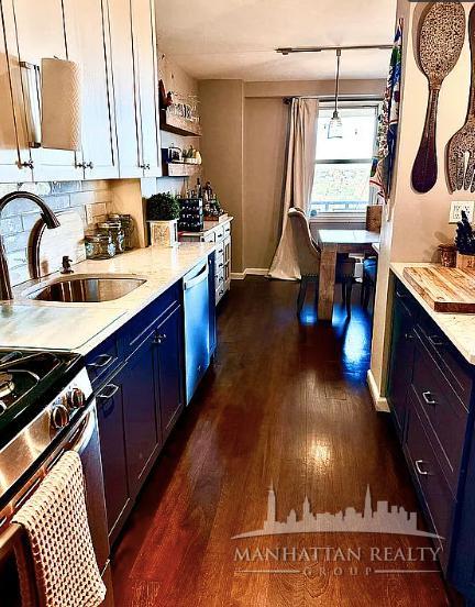 kitchen featuring dark wood finished floors, blue cabinetry, a sink, light countertops, and stainless steel dishwasher