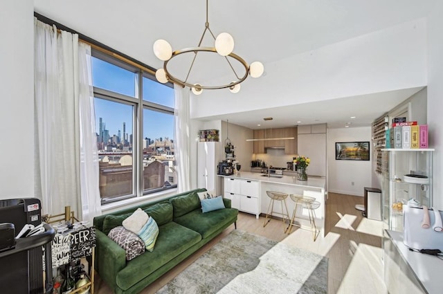 living room with sink, light hardwood / wood-style floors, and a notable chandelier