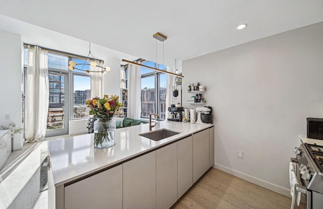 kitchen with decorative light fixtures, a view of city, light countertops, stainless steel range with gas cooktop, and a sink