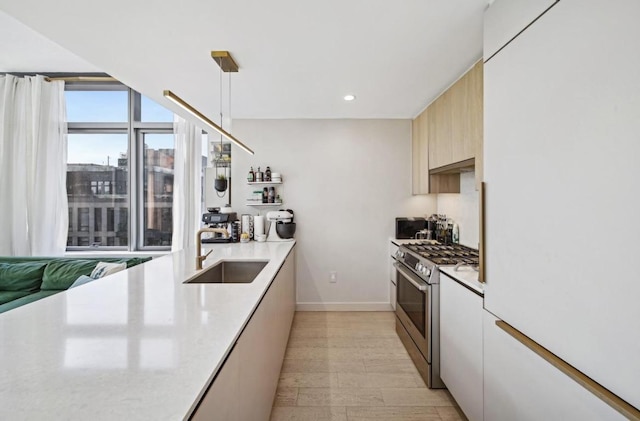 kitchen featuring sink, decorative light fixtures, and stainless steel gas range oven