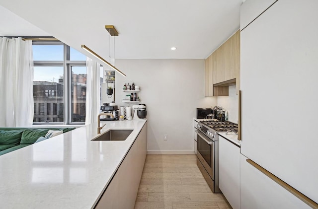 kitchen featuring decorative light fixtures, light countertops, a sink, and gas stove