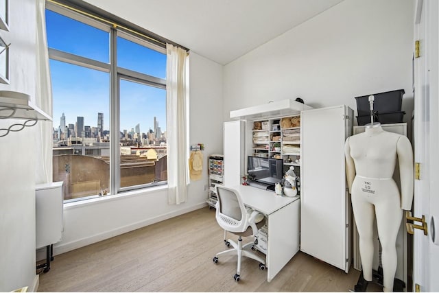 office area featuring light wood-style flooring, a view of city, and baseboards