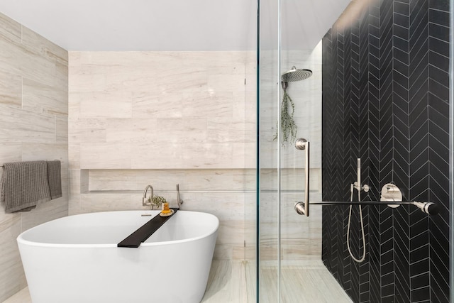 bathroom featuring a tile shower, tile walls, and a soaking tub