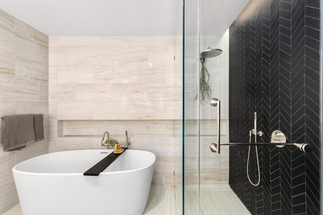 215 W 28th St Unit 2C, New York City, NY 10001 - bathroom featuring tile walls, a tile shower, and a freestanding tub