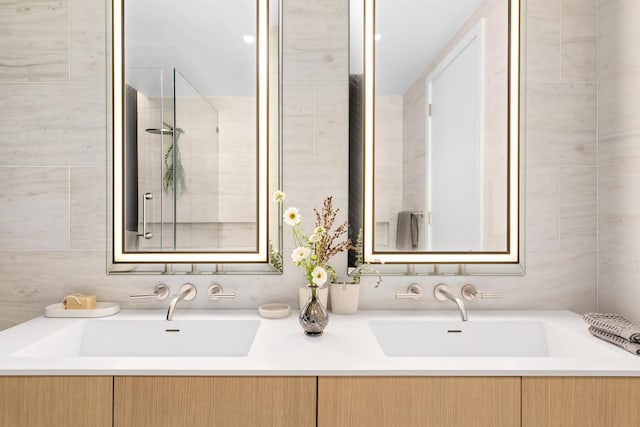 bathroom with double vanity, tile walls, a tile shower, and a sink