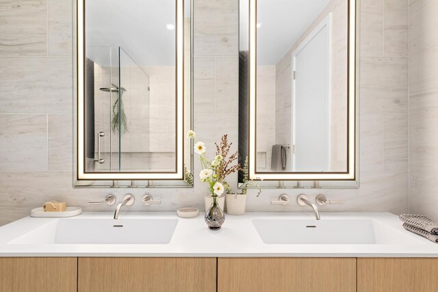 215 W 28th St Unit 2C, New York City, NY 10001 - bathroom featuring tile walls, double vanity, and tiled shower