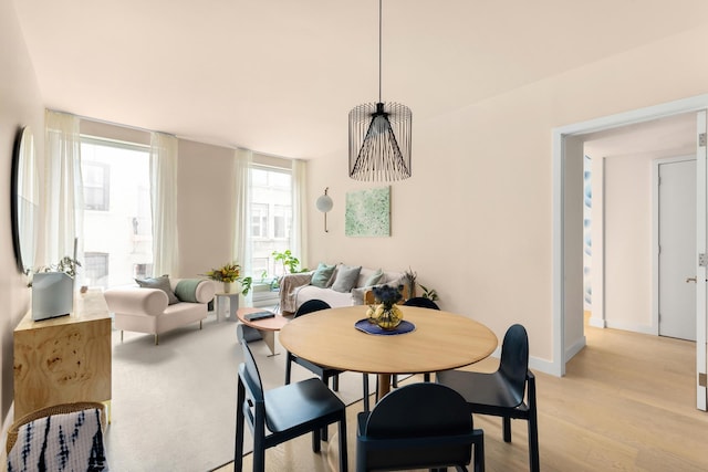 dining space featuring baseboards and light wood-type flooring
