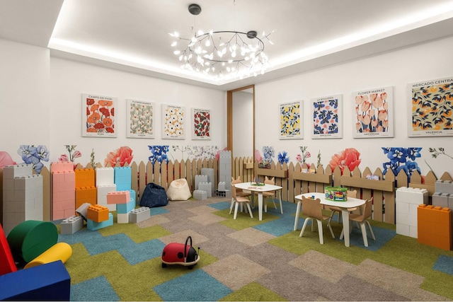 rec room with a tray ceiling, carpet, and an inviting chandelier