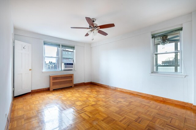 unfurnished room with light parquet flooring, radiator, and ceiling fan