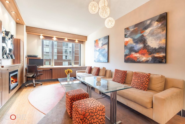 living area with recessed lighting, a lit fireplace, and wood finished floors