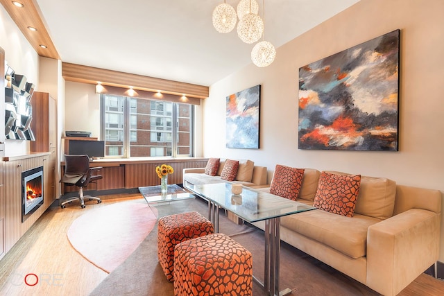 living area featuring recessed lighting, a warm lit fireplace, and wood finished floors