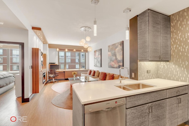 kitchen featuring dishwasher, hanging light fixtures, a sink, and light countertops