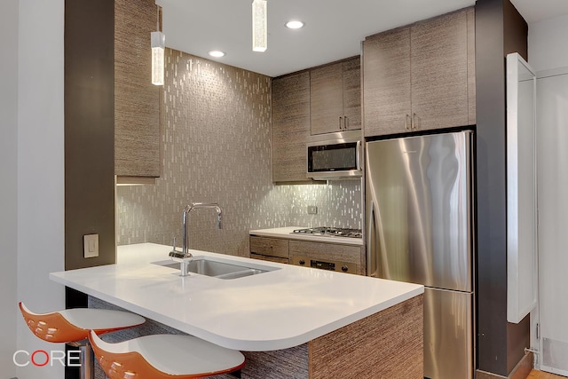 kitchen featuring decorative backsplash, stainless steel appliances, light countertops, a sink, and recessed lighting