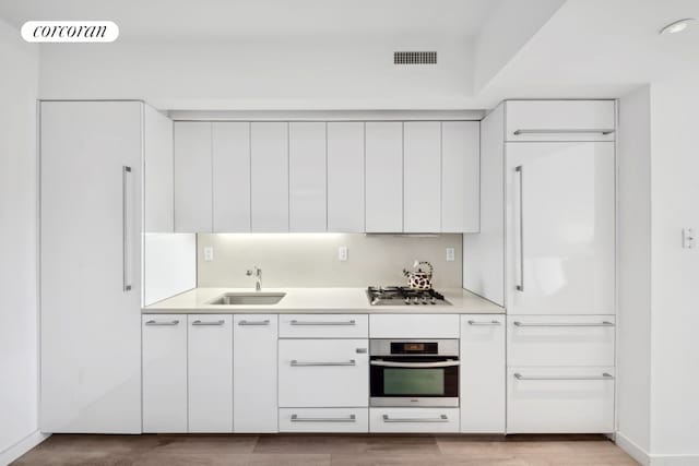 kitchen featuring sink, stainless steel appliances, white cabinets, and light wood-type flooring