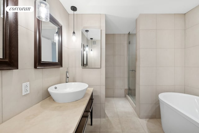 bathroom featuring a stall shower, tile walls, tile patterned flooring, a freestanding bath, and vanity