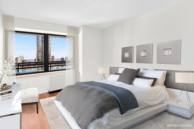 bedroom featuring a view of city and wood finished floors