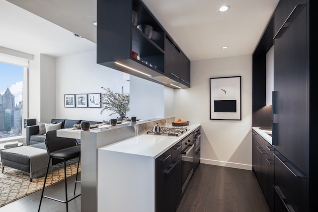 kitchen featuring dark wood-type flooring, a breakfast bar, built in fridge, stainless steel gas cooktop, and kitchen peninsula