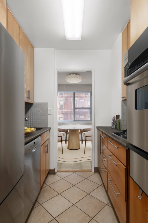 kitchen with light tile patterned flooring, stainless steel appliances, and decorative backsplash