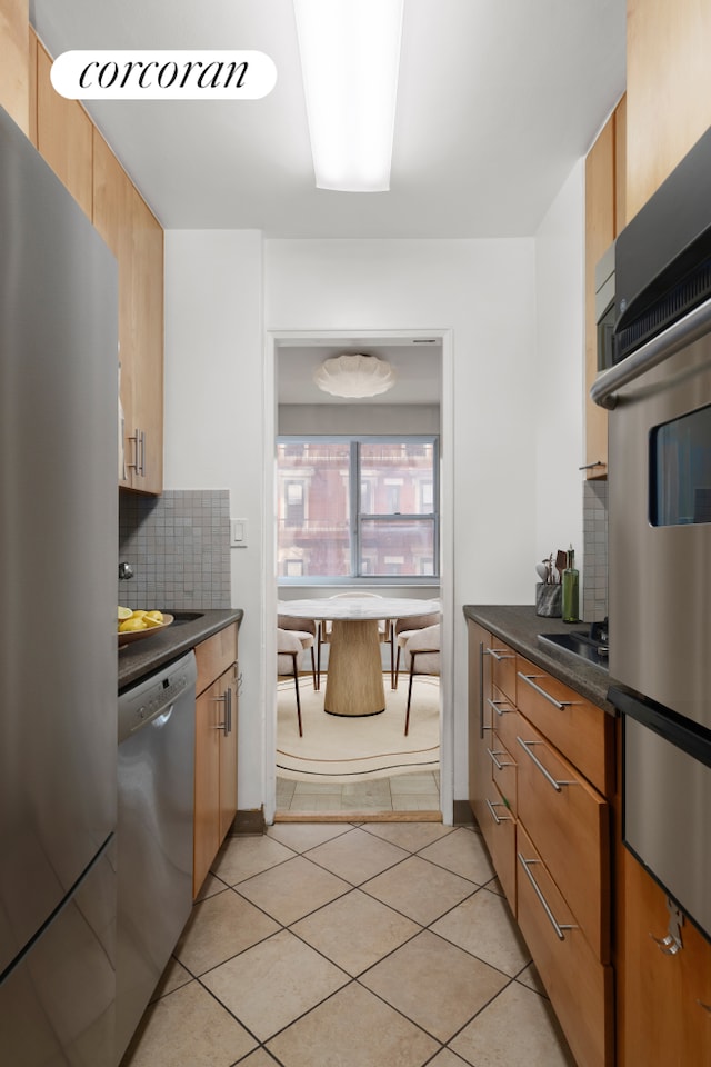 69 W 9th St Unit 6B, New York City, NY 10011 - kitchen with appliances with stainless steel finishes, dark countertops, backsplash, and light tile patterned floors