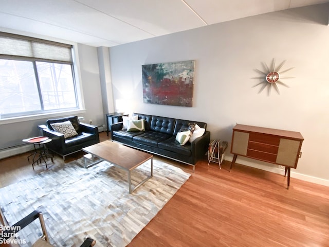 living area featuring a baseboard radiator, baseboards, and wood finished floors