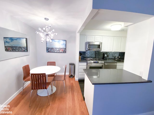 kitchen with decorative light fixtures, tasteful backsplash, white cabinets, kitchen peninsula, and stainless steel appliances