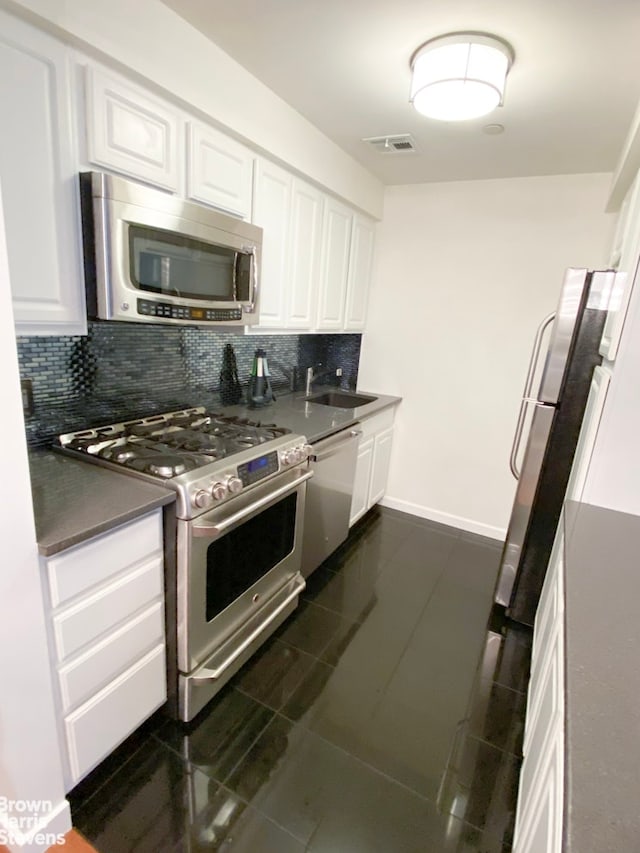 kitchen featuring visible vents, white cabinetry, appliances with stainless steel finishes, tasteful backsplash, and dark countertops